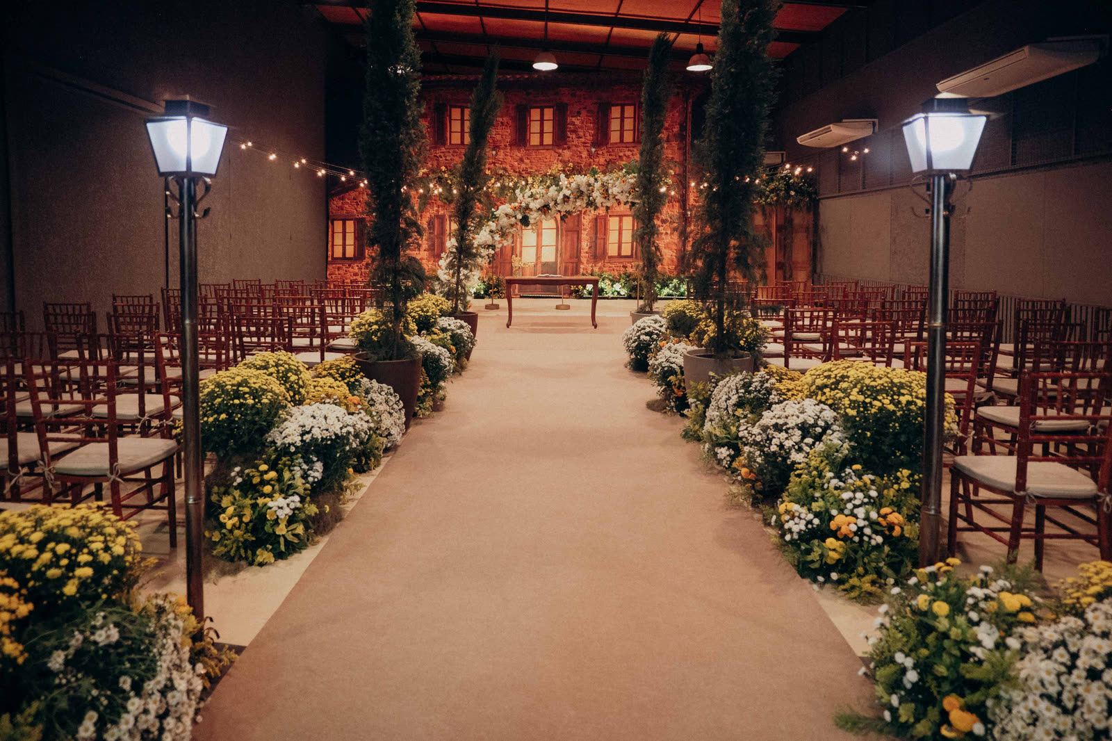 Cerimônia de casamento com lampiões, flores do campo e fachada toscana ao fundo