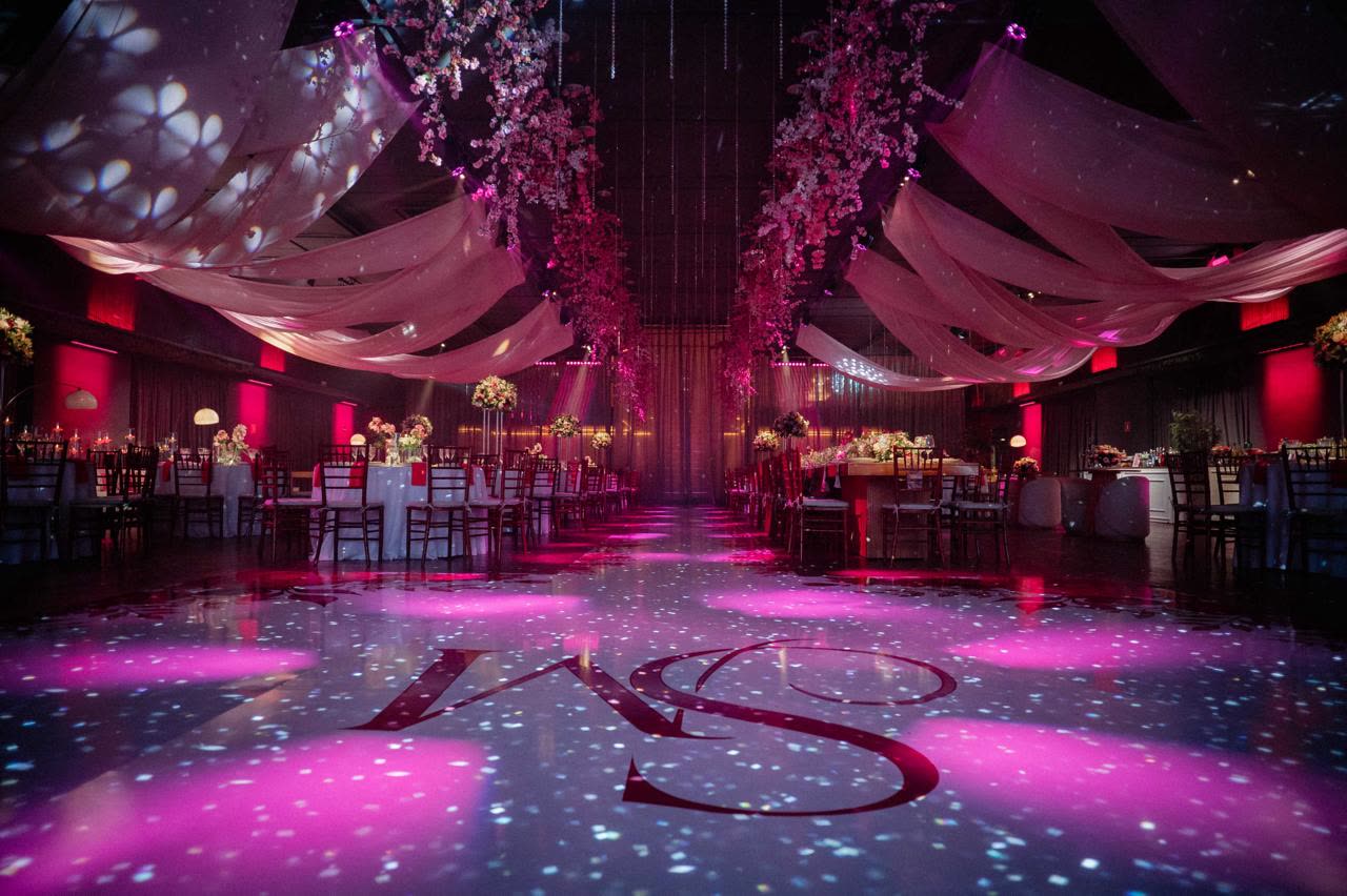 Pink dance floor with an illuminated monogram and fabric draped overhead