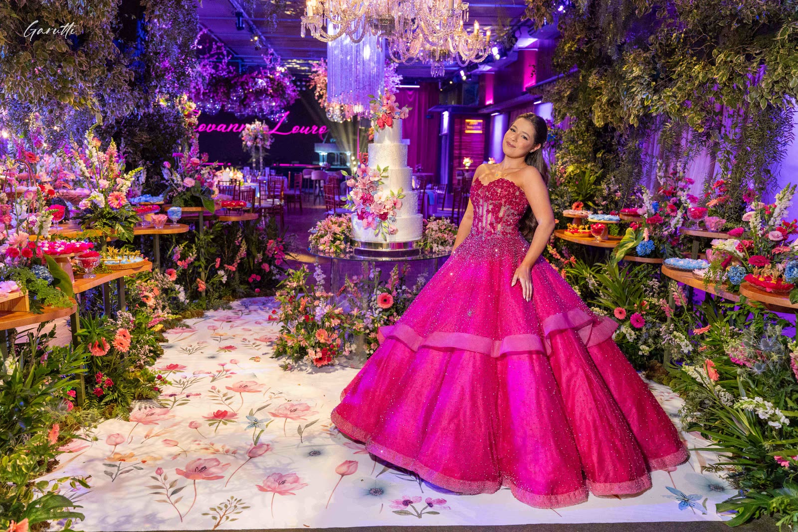 Debutante next to the cake in a setting of tropical flowers