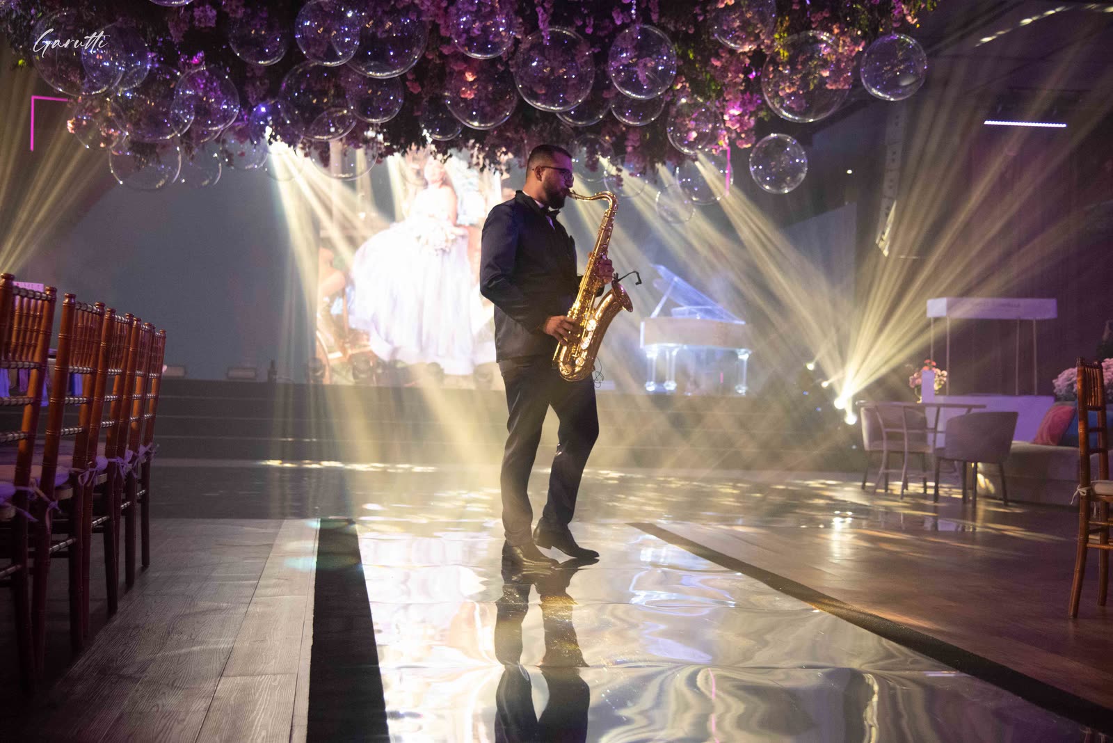 Saxophonist on the dance floor under light beams