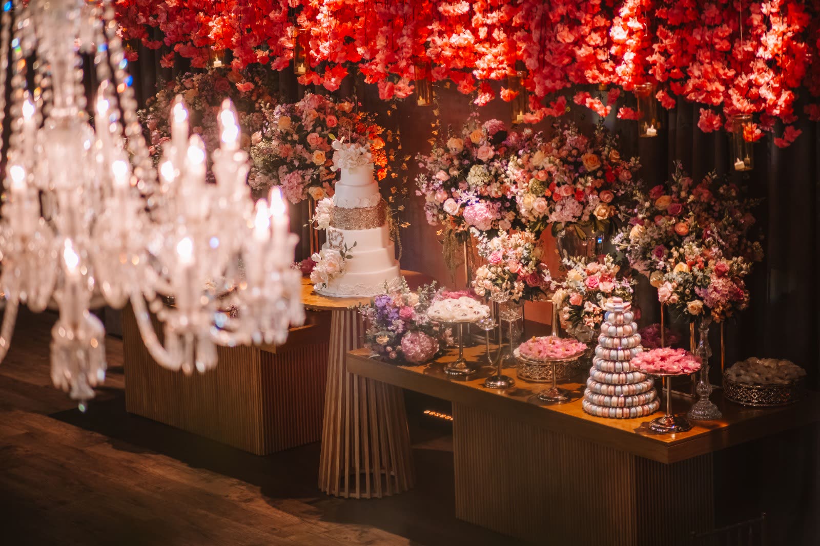 Dessert table under a crystal chandelier and a ceiling of red flowers