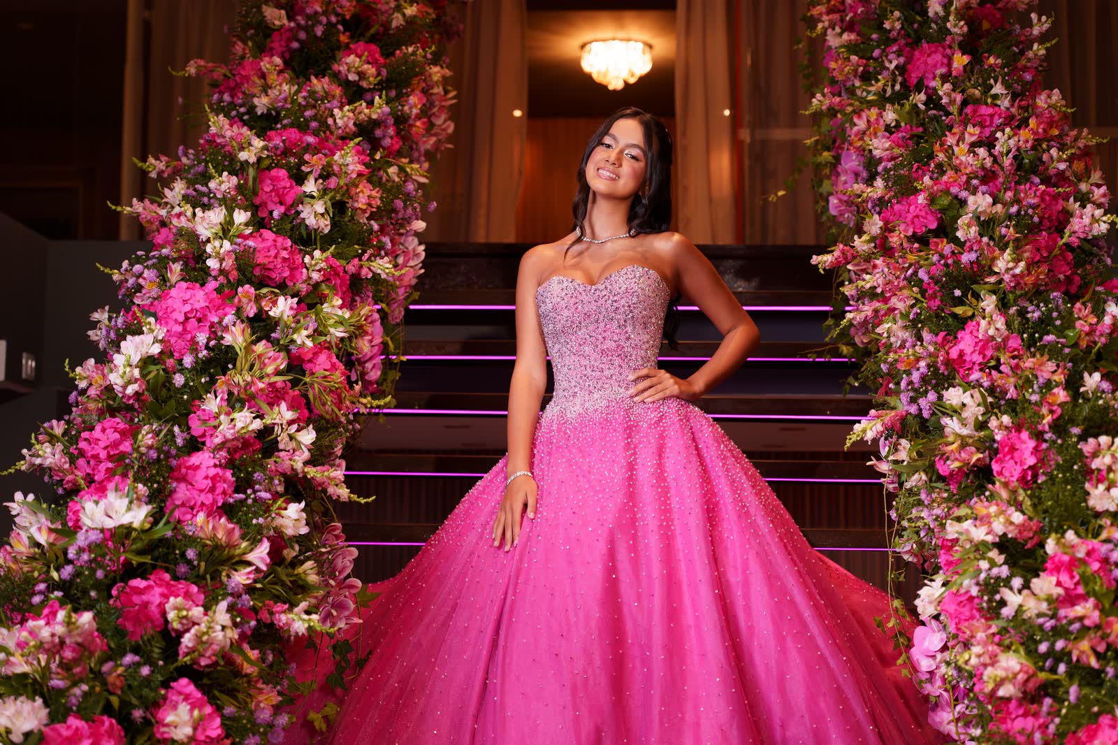 Debutante de vestido rosa na escadaria decorada com flores