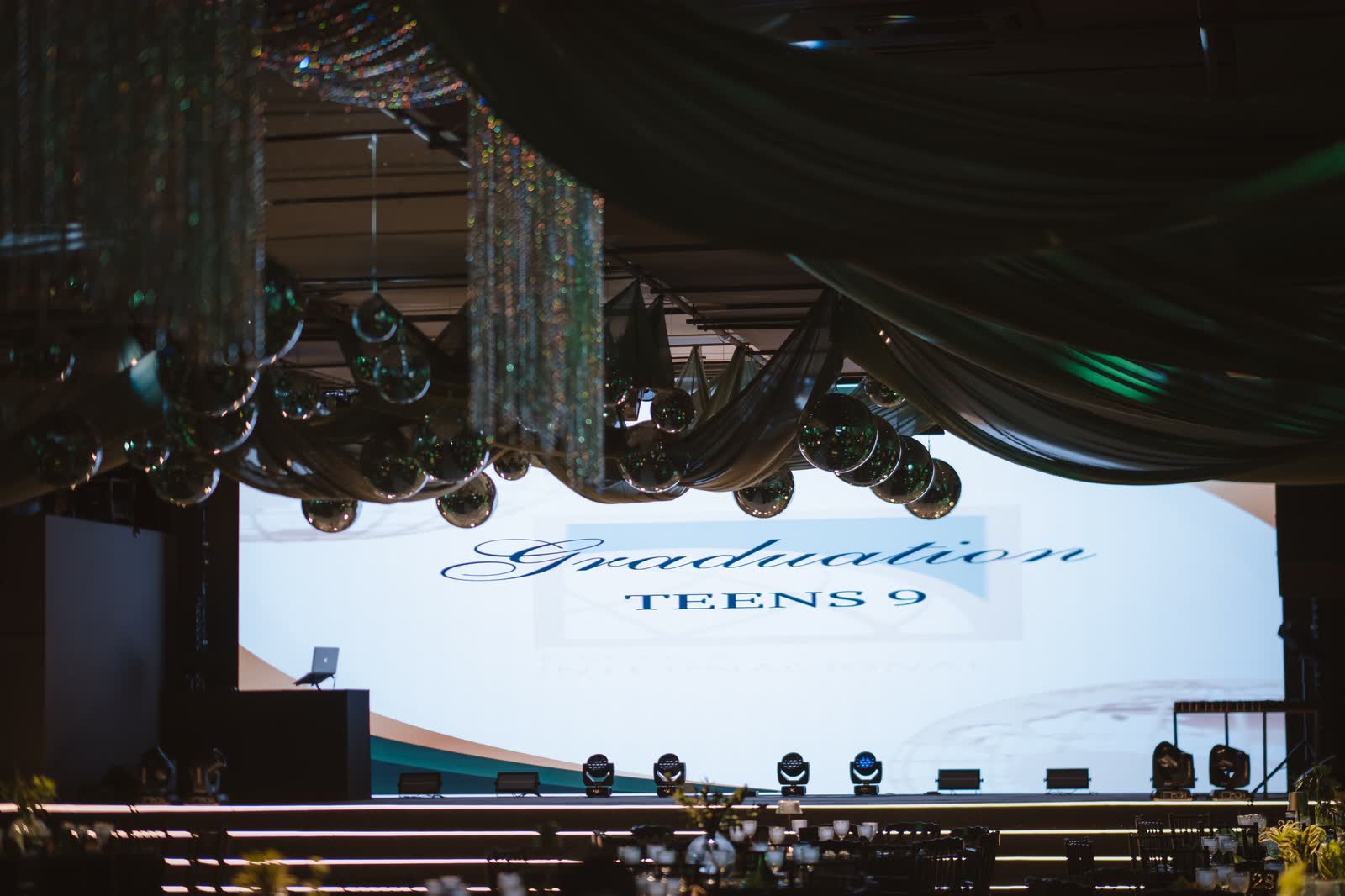 Telão do baile de formatura no salão com tecidos verdes e cortinas de cristal