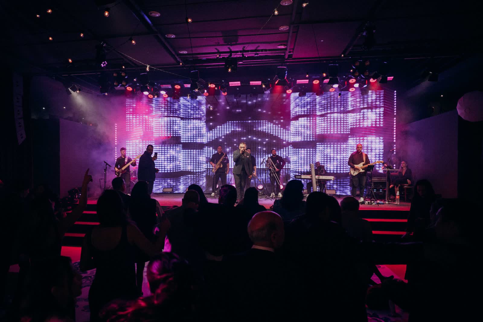 Banda no palco com parede de LED e plateia à frente