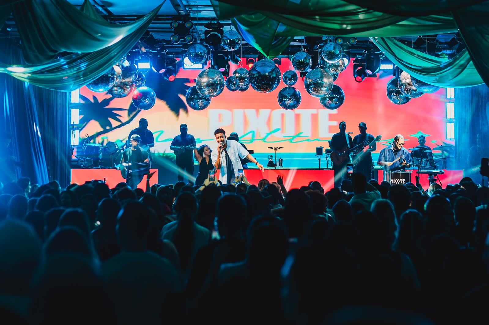 Banda ao vivo diante de telão colorido e globos espelhados