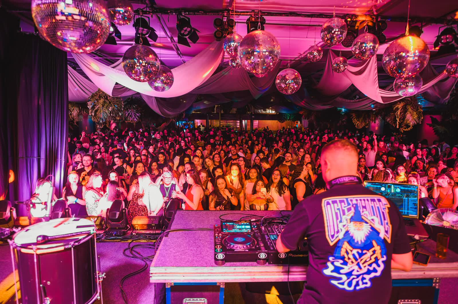 DJ comanda a pista lotada sob luz rosa