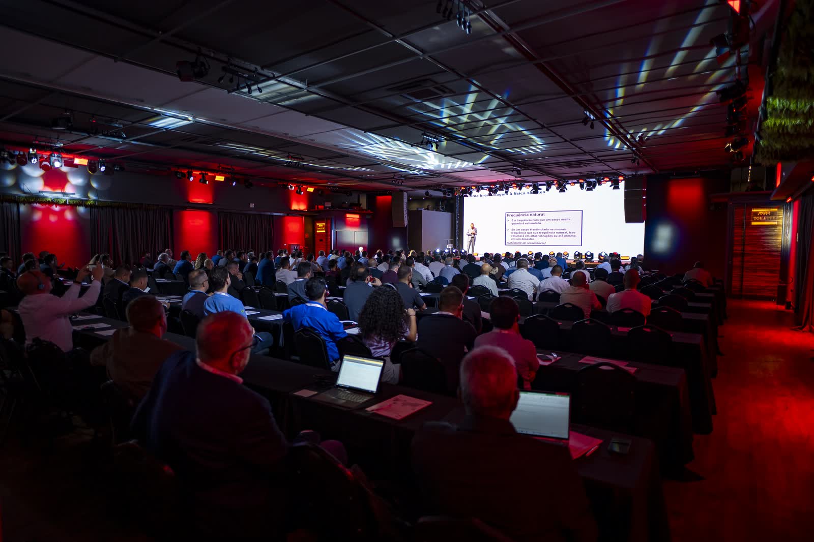 Participantes com notebooks acompanhando a apresentação no telão